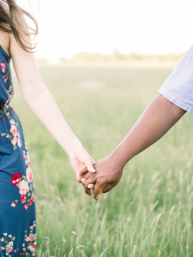 Mixed race engaged couple holding hands in a field in Princeton New Jersey