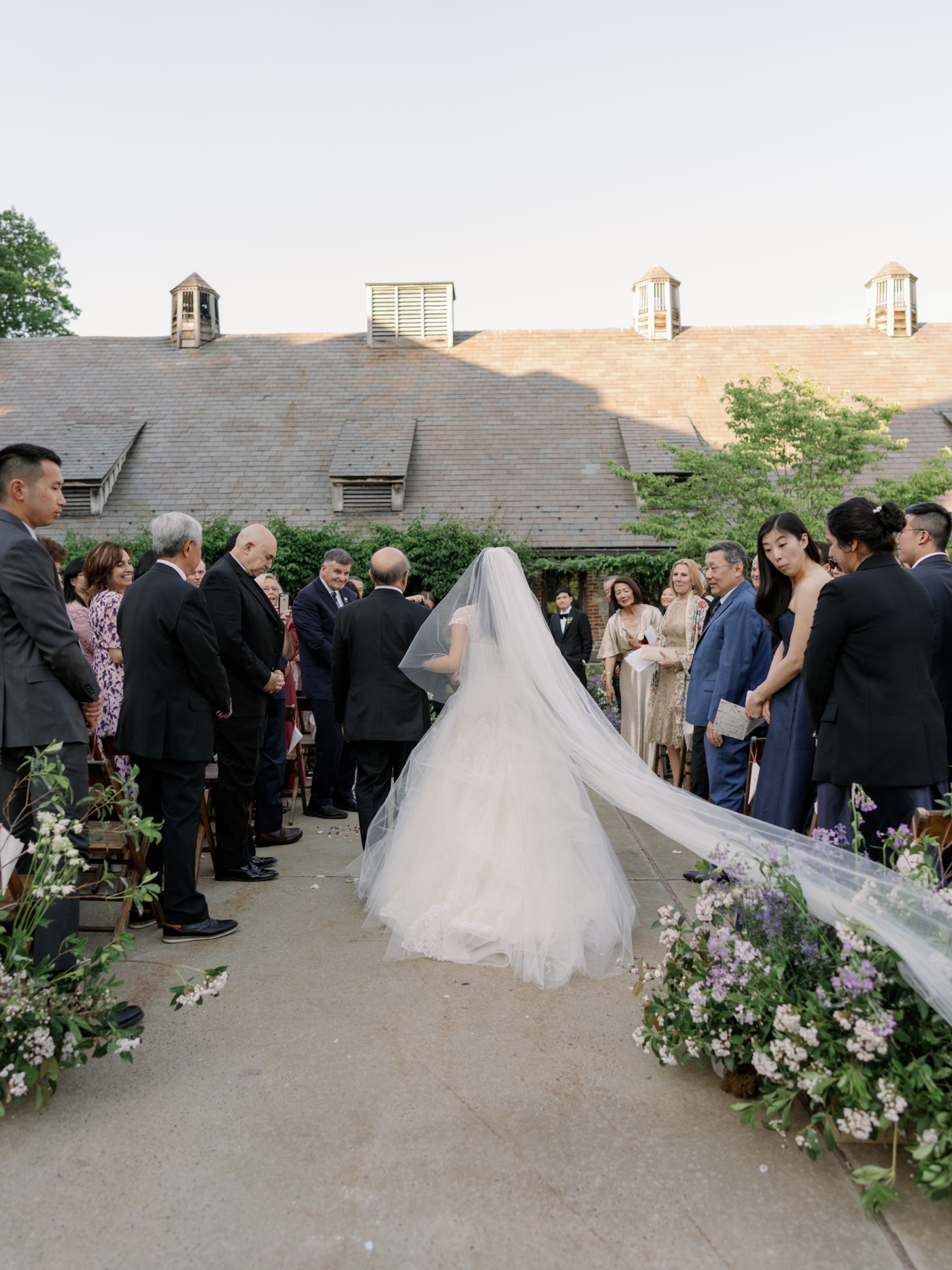 View from behind of bride and her father walking down the aisle during wedding ceremony at Blue Hill Farm