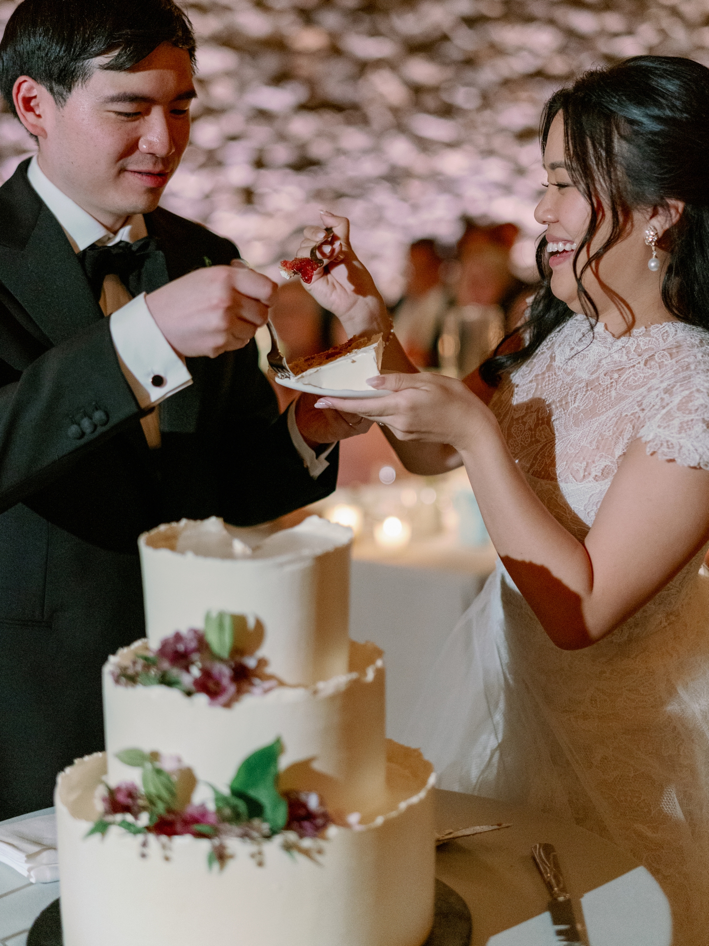 Bride and groom grabbing cake on their forks during wedding cake cutting 