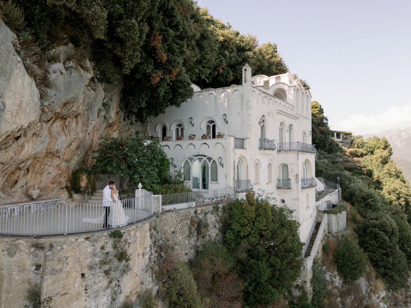 Bride and groom kissing on the cliffside balcony at Villa La Rondinai